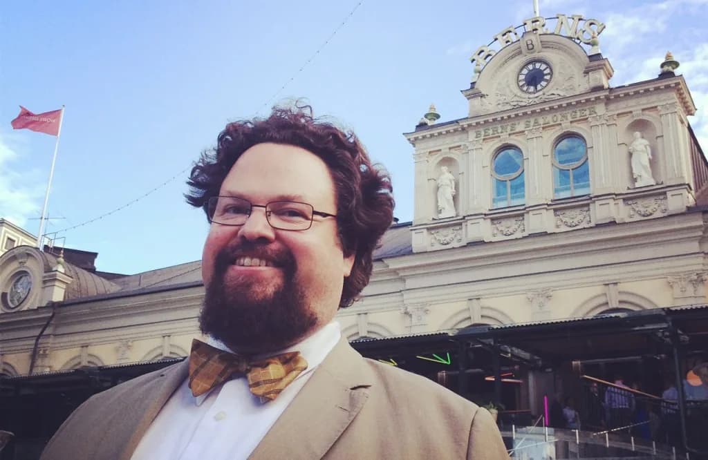 Edward Blom i beige kavaj och rutig fluga framför Berns salonger i Stockholm